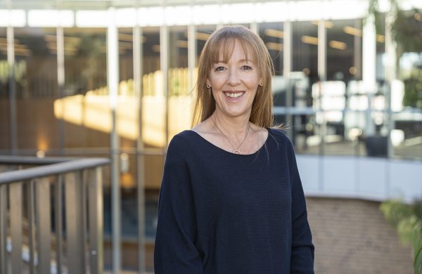 Renee, smiling to camera, standing outdoors in front of a building