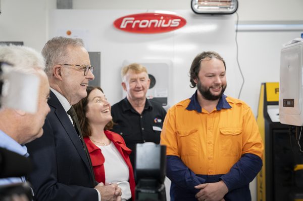 Prime Minister Albanese conversing with a Bendigo TAFE apprentice wearing hi-vis in the clean energy lab.
