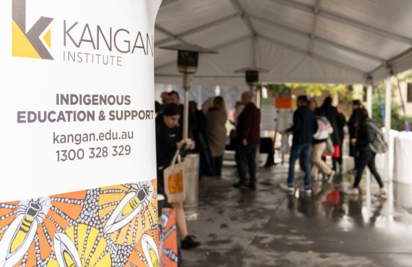 Close up of a branded banner saying "Indigenous Education & Support" with blurred people in the background.